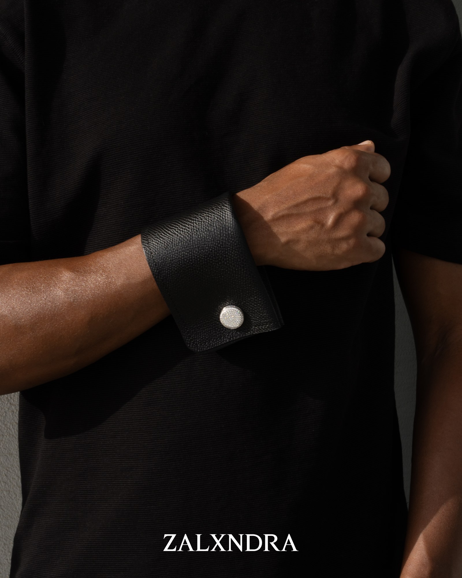 VALEUR black leather cuff worn on the wrist with a circular cufflink